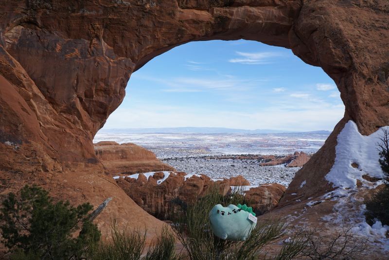 Pusheeno beneath a huge sandstone arch with snow on the ground
