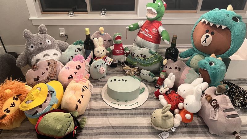 A mint-green birthday cake reading Happy B-Day Pusheeno, surrounded by a crowd of plush friends